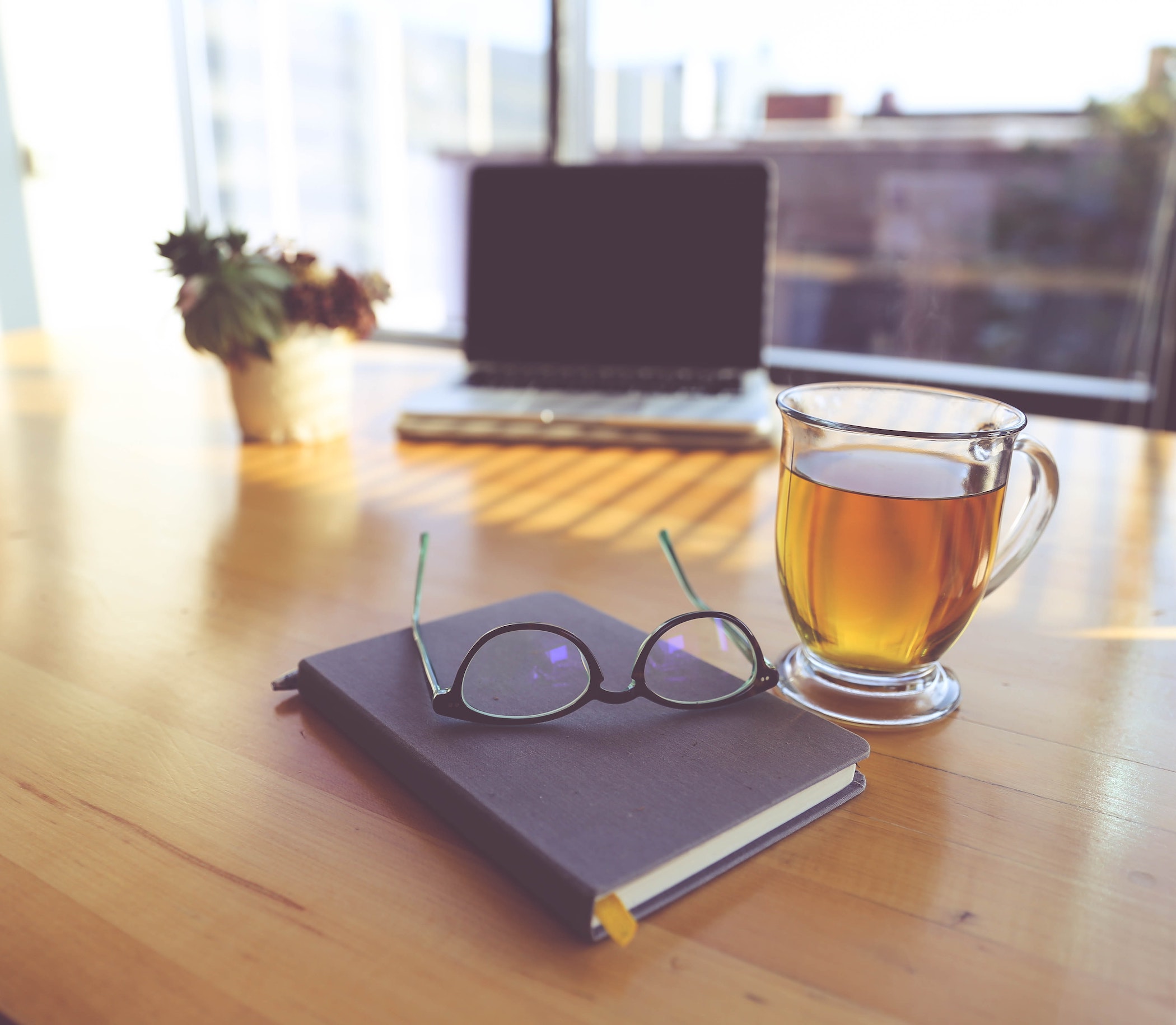 Glasses on a book next to a cup of tea